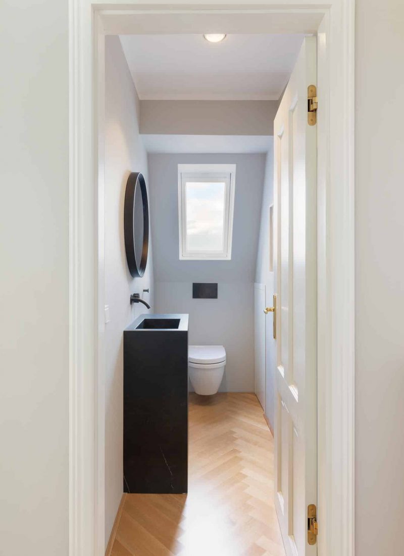 Parkettboden, schwarze Armaturen von CEA und runder Spiegel