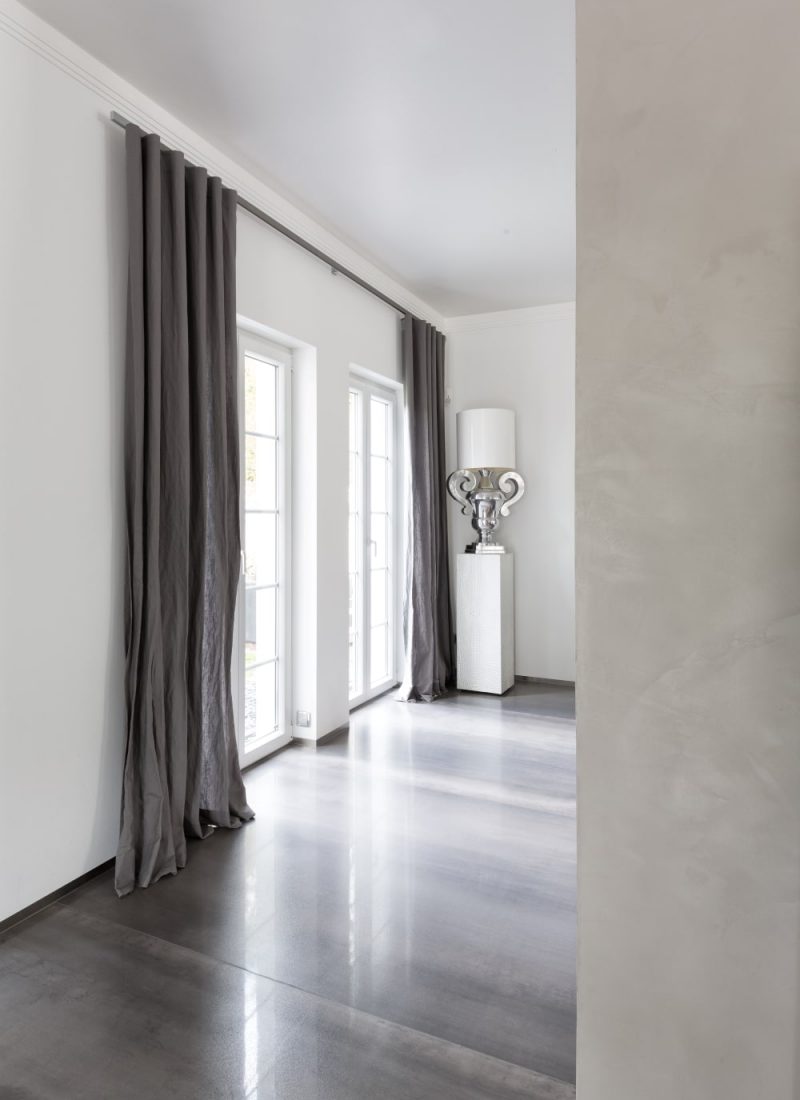 Ein Raum mit weißen Wänden und grauen Vorhängen, der ein Gefühl von Sauberkeit und Ruhe ausstrahlt. | casaceramica