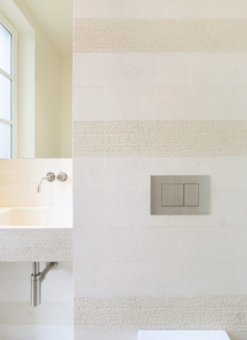 Natursteinwand in Beige und WC Betätigungsplatte